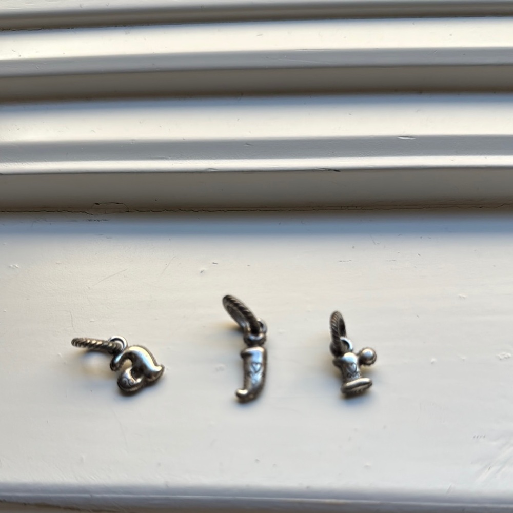 Silver charm letters “a” “j” and “r”. Each letter has a tiny design.